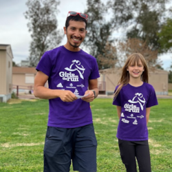 Girls on the run coach in purple shirt holding index cards and standing with participant